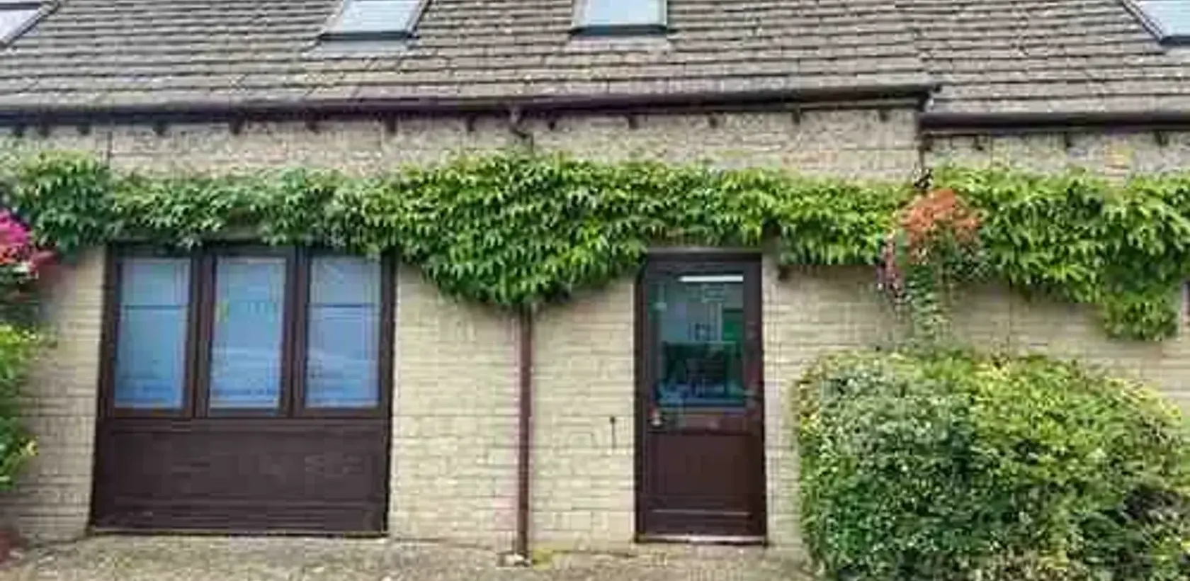 The front of Active Therapy Clinic at Whiteway Court, Cirencester, a Cotswold stone building covered in ivy