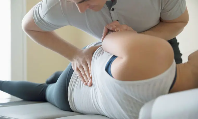 A physiotherapist treating a patient's lower back on a treatment couch
