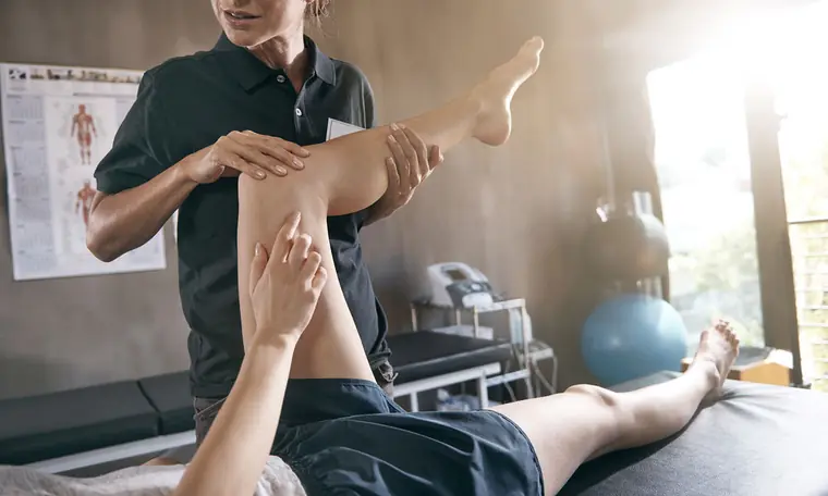 A clinician guiding a patient through a leg rehabilitation exercise